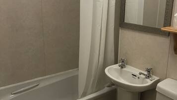 A bathroom with a bathtub, sink, toilet, and a mirror with a textured frame.