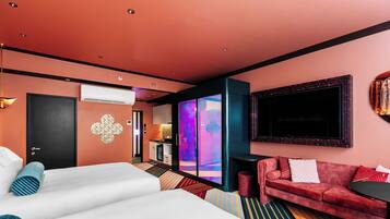 A hotel room with a large bed, a red sofa, a small table, and a TV.