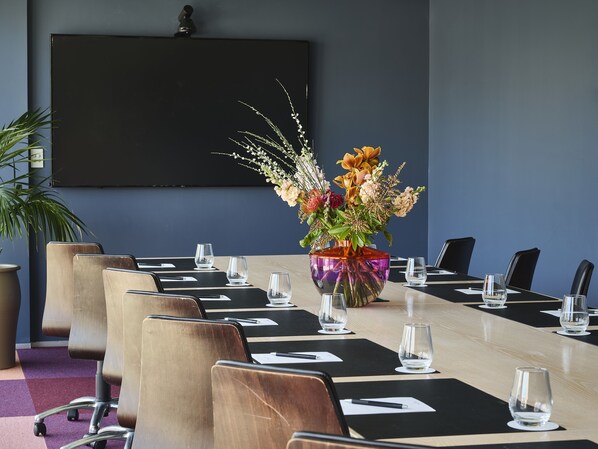 A conference room with a long table, chairs, and a large vase with flowers.
