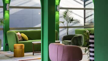 Un interior moderno con un sofá verde, un sillón morado y una pequeña mesa redonda.