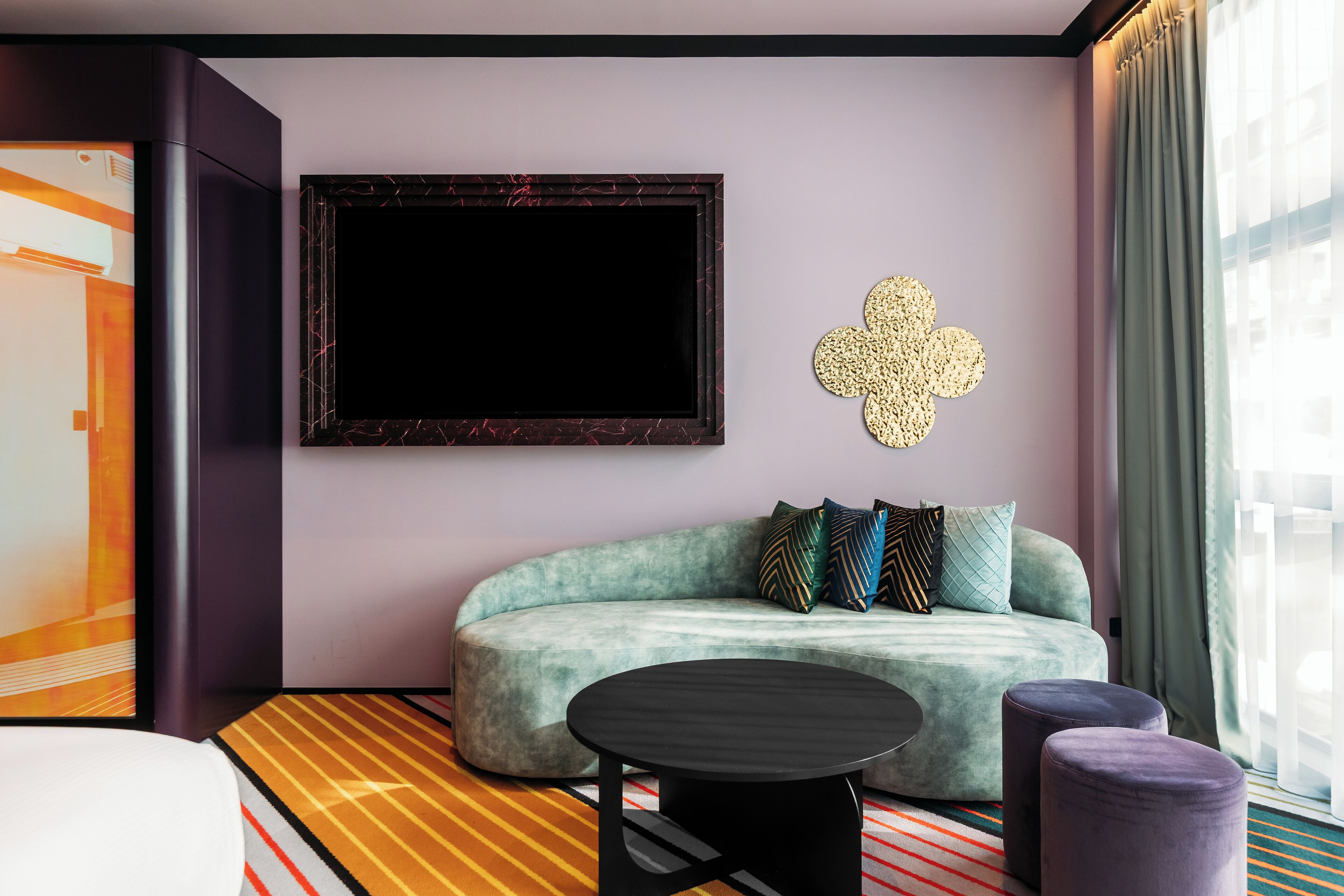 A modern living room with a sofa, a round coffee table, and a decorative wall piece.