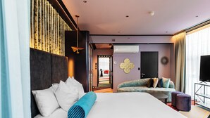 Une chambre d’hôtel moderne avec un grand lit, un canapé, une télévision et un balcon.