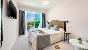 Ein modernes Hotelzimmer mit einem großen Bett, einem Fernseher, einem kleinen Tisch und Blick ins Freie.