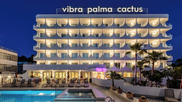 Ein mehrstöckiges Hotel mit Poolbereich, Palmen und einem Schild mit der Aufschrift 'Vibra Palma Cactus'.