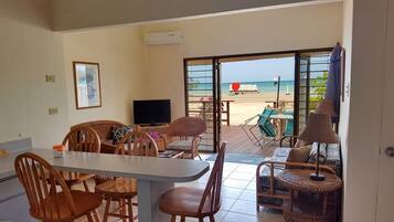 A dining area with a table and chairs, a television, and a view of the beach.