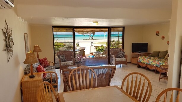 Una habitación con comedor, sofá, televisión y vista a la playa.