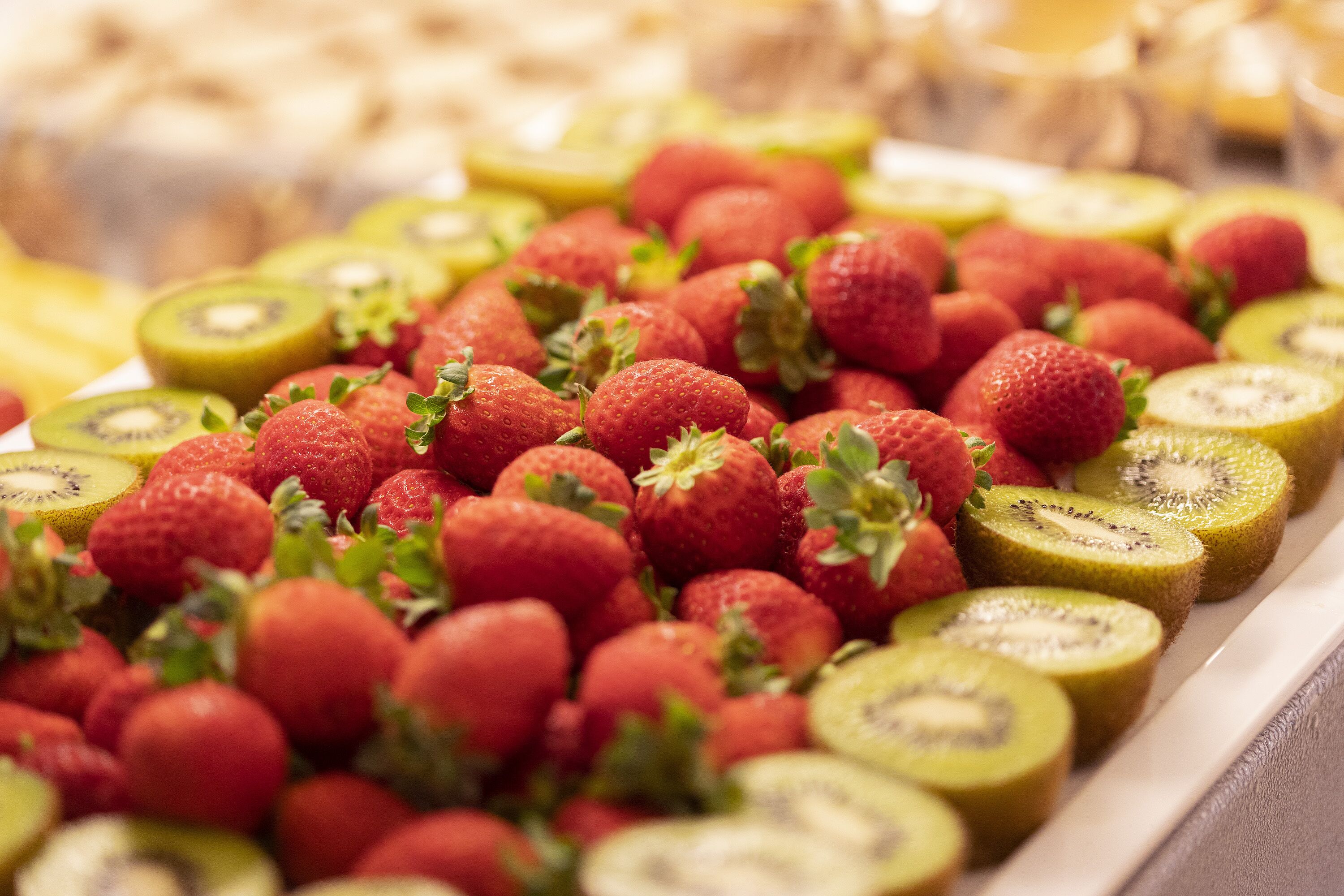A tray of sliced kiwi and strawberries.