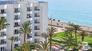 Un hotel con piscina, palmeras y vistas al mar.