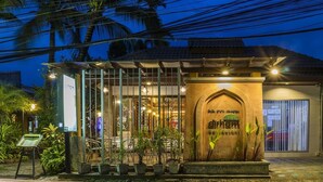 A restaurant with a covered outdoor seating area, a signboard, and a decorative archway. - Bangtao Beach Chalet (Choeng Thale)