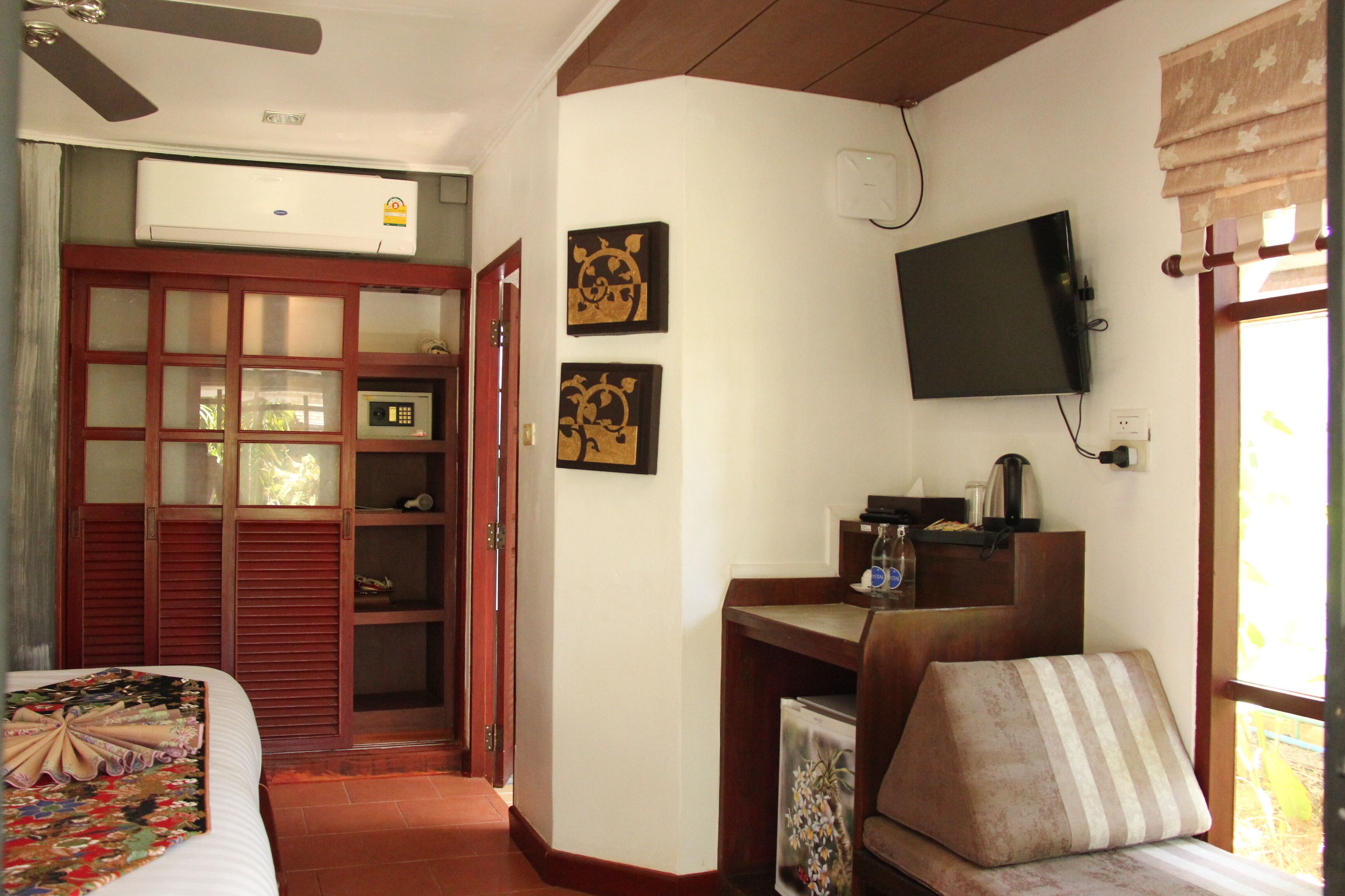 A hotel room with a bed, a desk, a television, and a window with curtains.