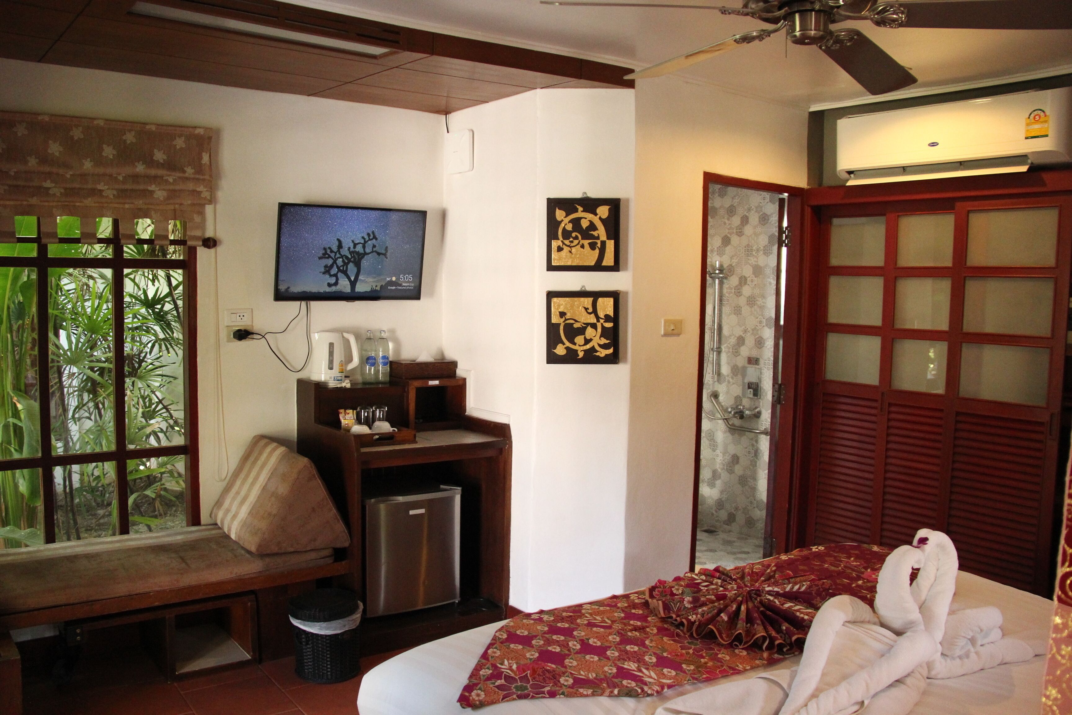 Une chambre d’hôtel avec un lit, un bureau équipé d’un ordinateur, une télévision et des œuvres d’art accrochées au mur.