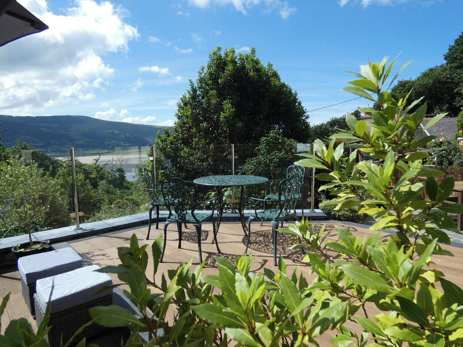 Um pátio externo com mesa redonda e cadeiras, cercado por vegetação e com vista para uma paisagem deslumbrante.