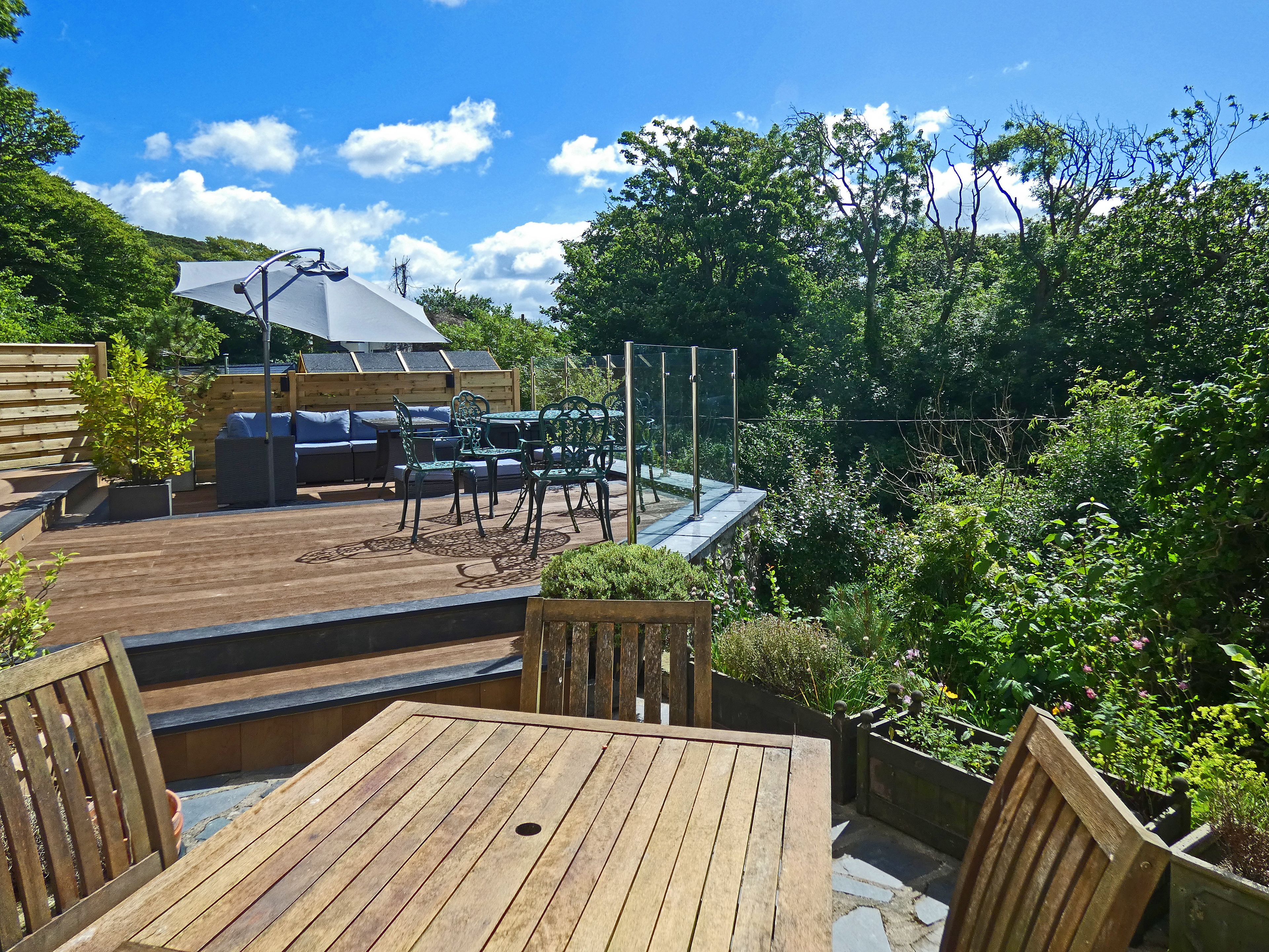 A wooden deck with outdoor furniture, including a table and chairs, and a covered seating area with a table and chairs.