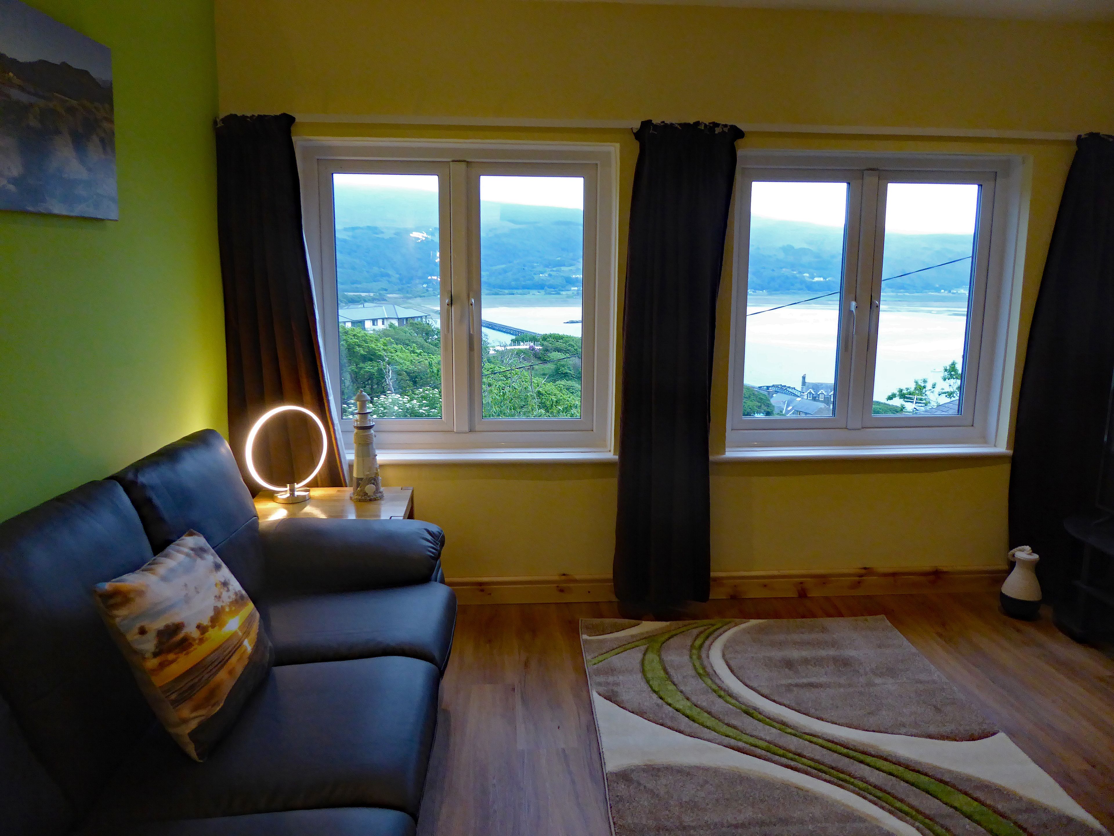 A living room with a sofa, a rug, and a view of a bridge and water.