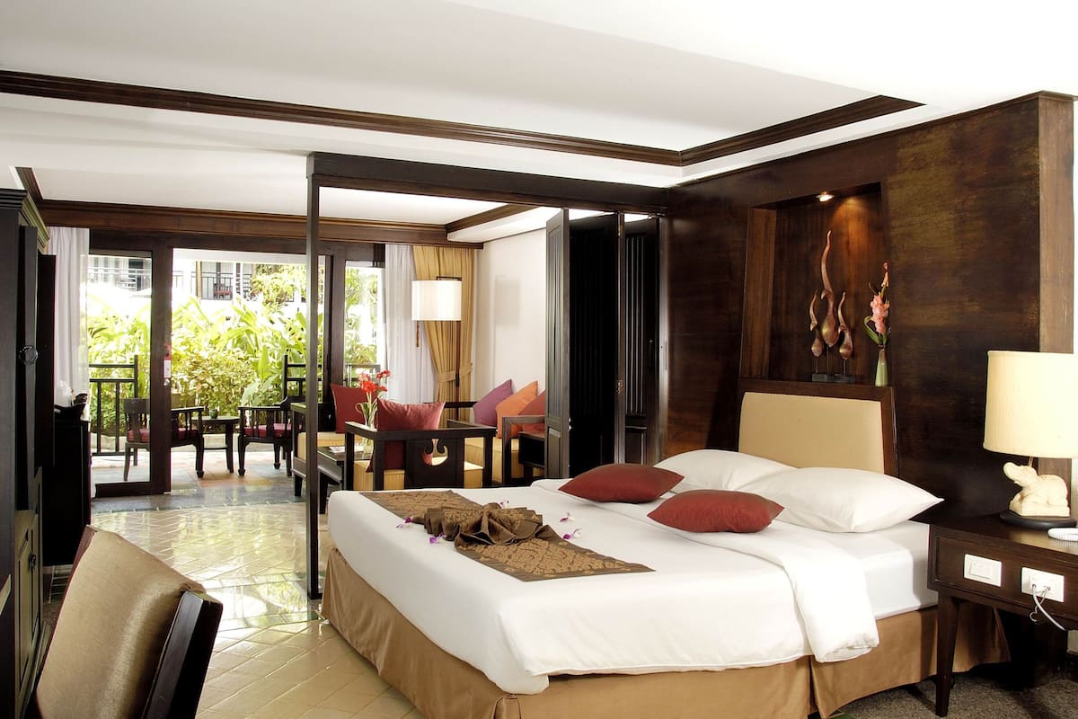 A hotel room with a large bed, a desk, a chair, and a view of the outdoors.