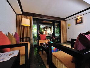 Ein Hotelzimmer mit einer Couch, einem Esstisch und Blick ins Freie.