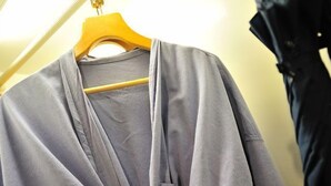A grey cardigan hanging on a wooden hanger. - Kudo Hotel (Patong)
