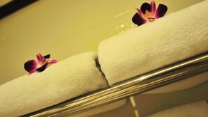 A hotel room with a bed, a mirror, and a towel with a flower on it. - Kudo Hotel (Patong)