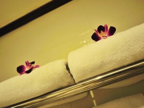 Een hotelkamer met een bed, een spiegel en een handdoek met een bloem erop.