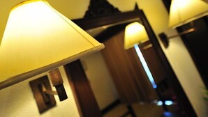 A hallway with three wall-mounted lamps and a mirror reflecting part of the room. - Kudo Hotel (Patong)