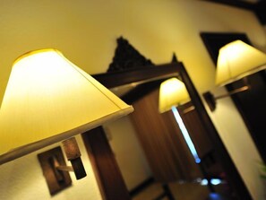 Een gang met drie wandlampen en een spiegel die een deel van de kamer weerspiegelt.
