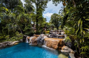 A natural pool surrounded by lush greenery and cascading waterfalls. - Khaolak Merlin Resort (Thai Mueang)