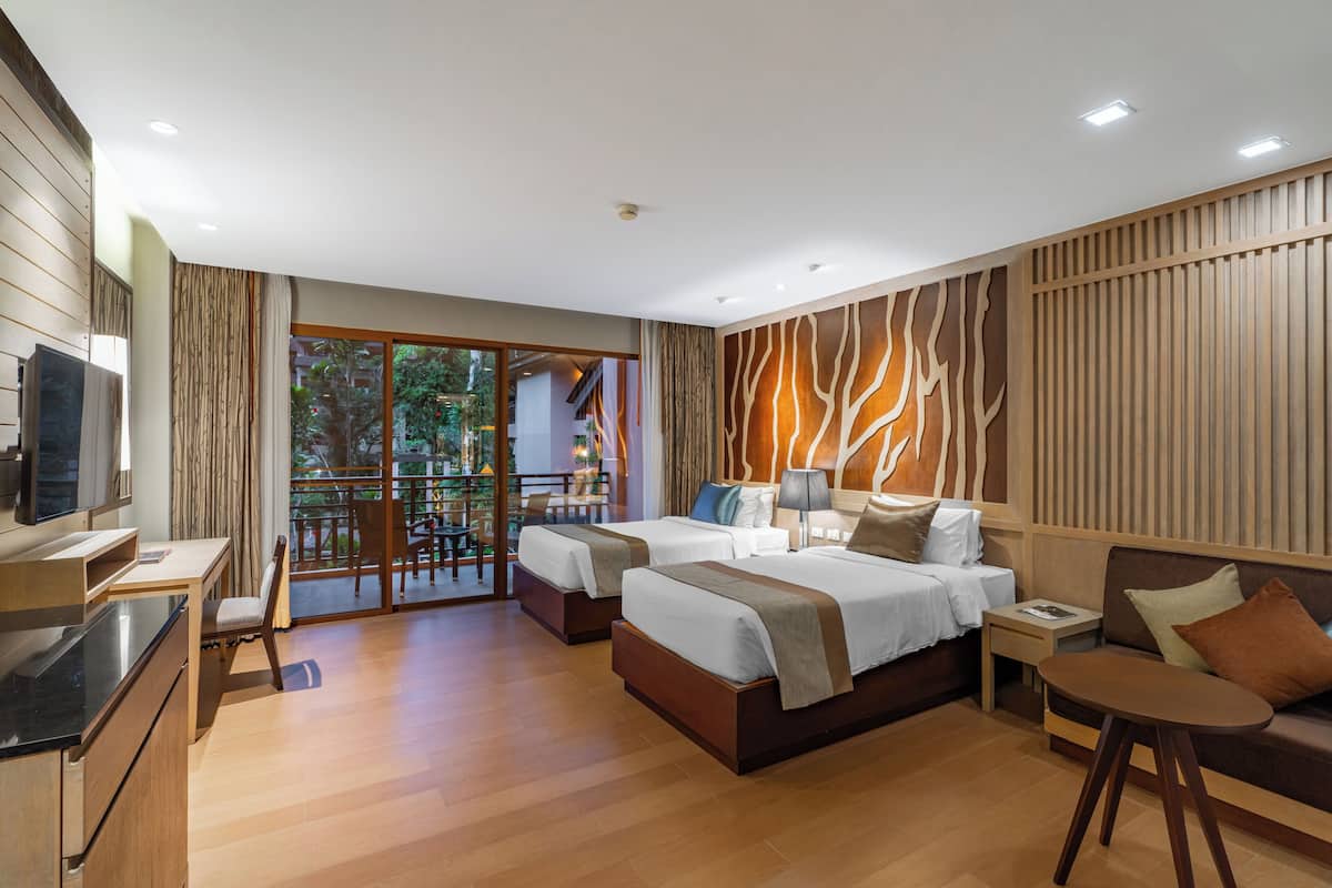 Une chambre d’hôtel moderne avec deux lits, un canapé, une télévision et un balcon donnant sur un paysage verdoyant.