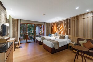 Una habitación de hotel moderna con dos camas, un sofá, un televisor y un balcón con vistas a zonas verdes.