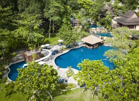 Un resort con una amplia piscina central, numerosas habitaciones y abundante vegetación.