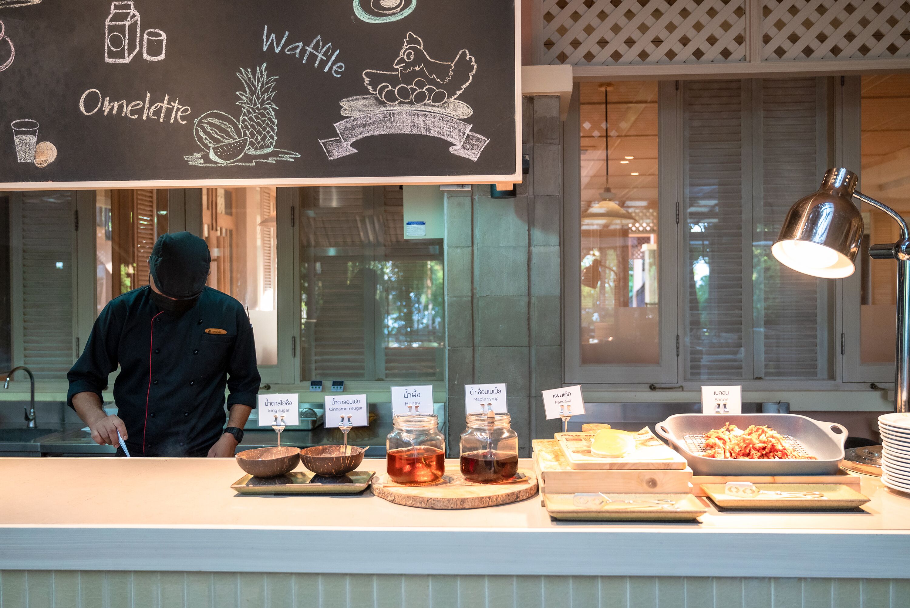 A breakfast counter with various food items and a chalkboard menu.
