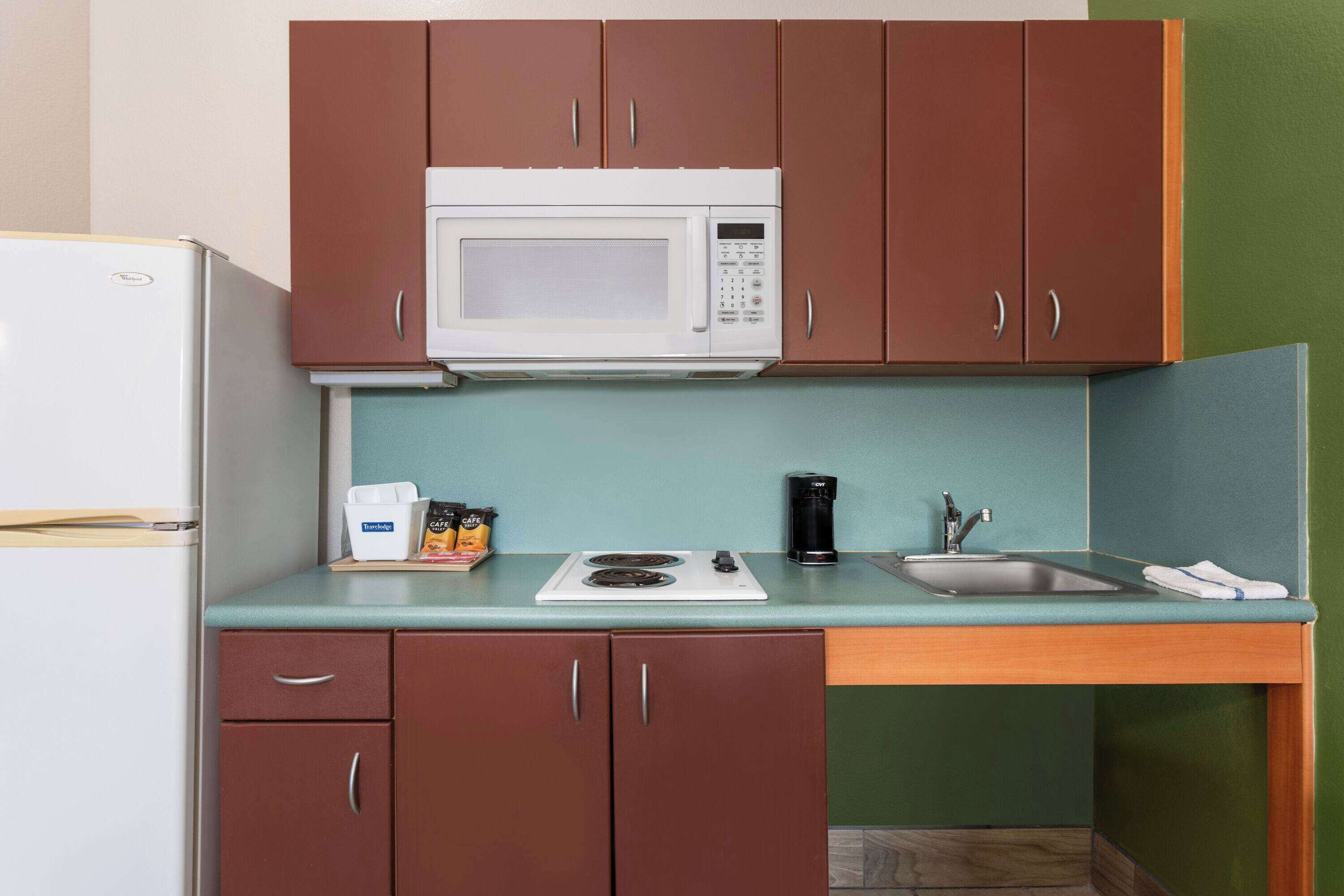 Una cucina compatta con forno a microonde, fornelli, lavandino e pensili.