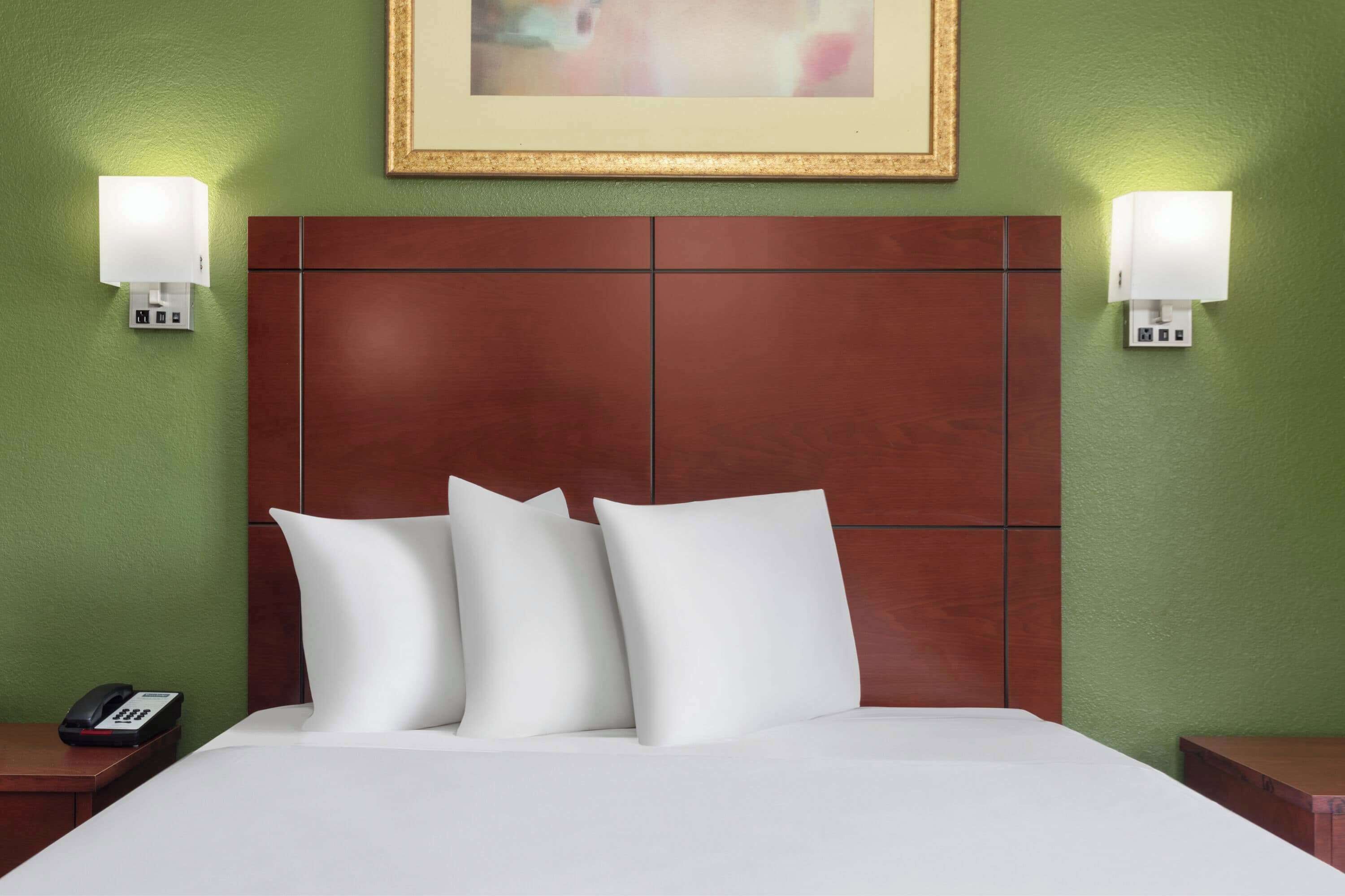 A hotel room with a large bed, two bedside tables, a telephone, and wall-mounted lights.
