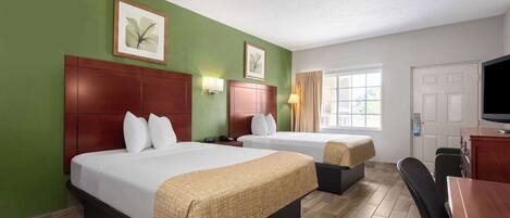 A hotel room with two beds, a desk, a chair, and a television.