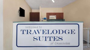 Un comptoir d’accueil avec une pancarte indiquant : « Bienvenue à TRAVELODGE SUITES d’Okeechobee. »