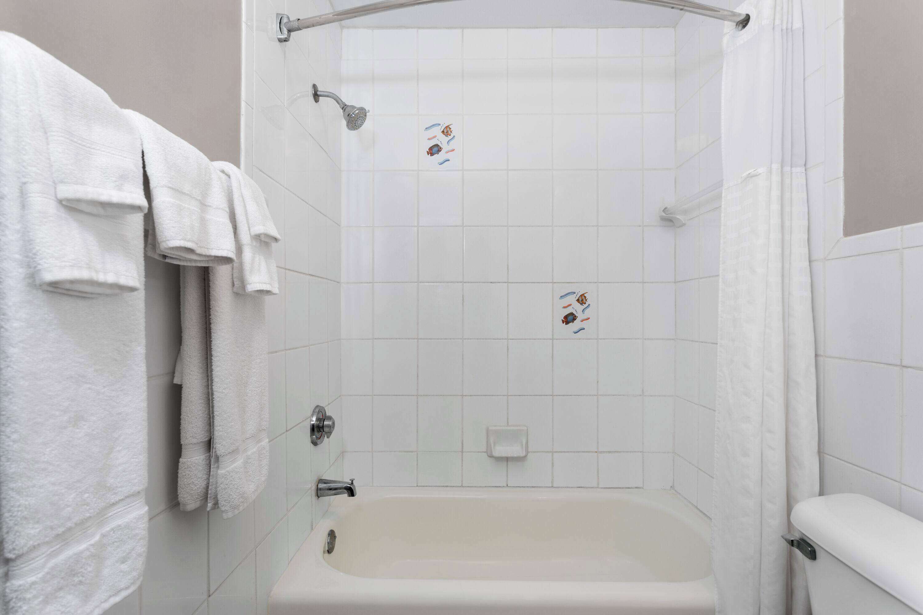 Une salle de bain avec une baignoire, une douche et des toilettes. Des serviettes sont accrochées au mur.