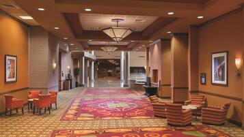 A hotel lobby with a patterned carpet, seating area, and a reception desk.