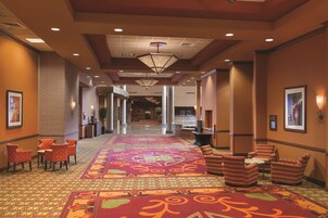 A hotel lobby with a patterned carpet, seating area with chairs, and a reception desk.