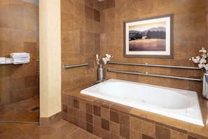 A bathroom with a bathtub, a handrail, a towel rack, and a framed picture on the wall. - Embassy Suites Omaha-La Vista/Hotel & Conference Center (La Vista)