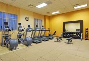 A gym with treadmills, elliptical machines, and weightlifting equipment.