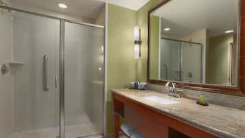 A modern bathroom with a glass shower enclosure, a sink with a marble countertop, and a large mirror.