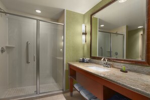 A modern bathroom with a glass shower enclosure, a sink with a marble countertop, and a large mirror. - Embassy Suites Omaha-La Vista/Hotel & Conference Center (La Vista)