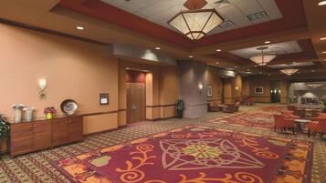 A hotel lobby with a patterned carpet, a reception desk, and a seating area with chairs and tables.