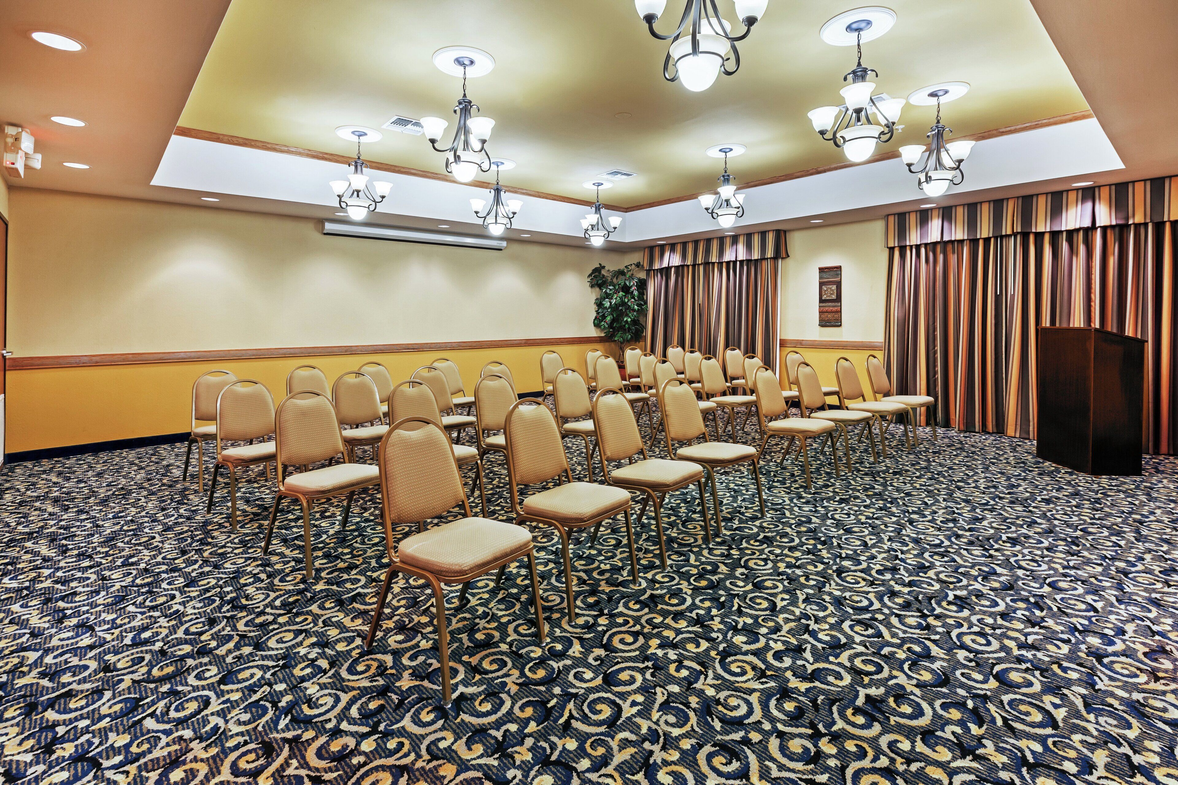 A conference room with rows of chairs, a patterned carpet, and ceiling lights.