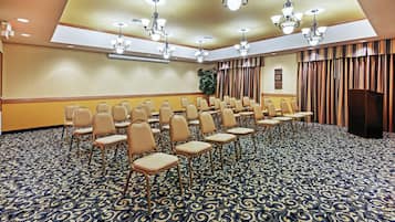 A conference room with rows of chairs, a patterned carpet, and ceiling lights.