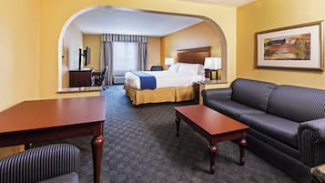 A hotel room with a bed, a sofa, a desk, and a TV.