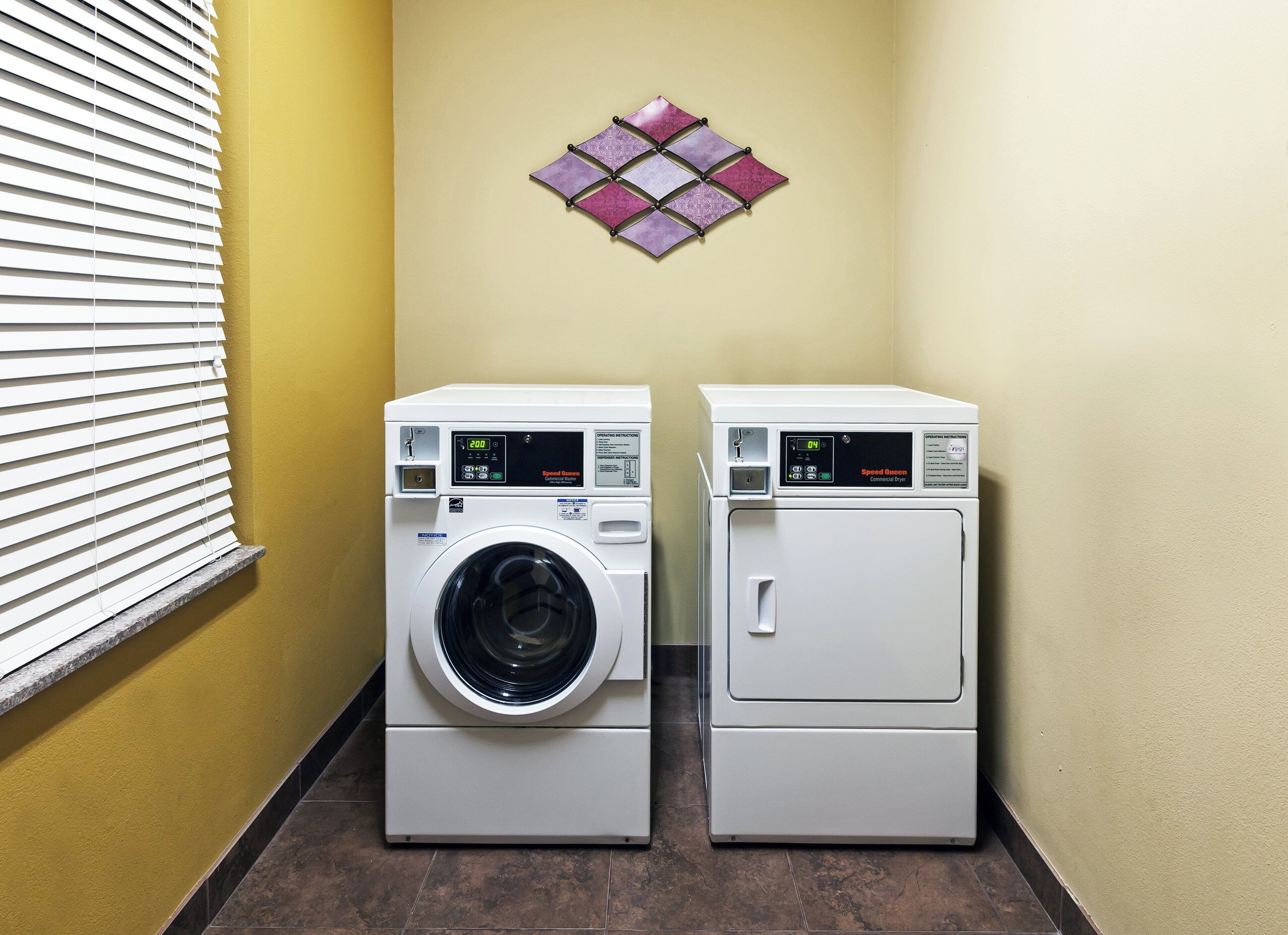 A laundry room with two white front-loading washing machines and a wall-mounted drying rack.