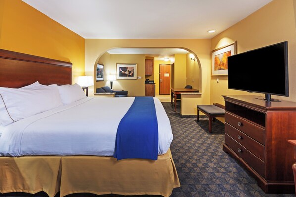 Una habitación de hotel con una cama grande, televisión, escritorio y una silla.