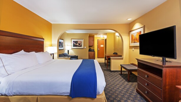Ein Hotelzimmer mit einem großen Bett, einem Schreibtisch, einem Fernseher und einer Kommode.