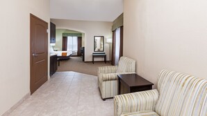 A hotel room with a sofa, a small table, a bed, a desk, and a mirror. - Holiday Inn Express Hotel & Suites Victoria by IHG (Victoria)