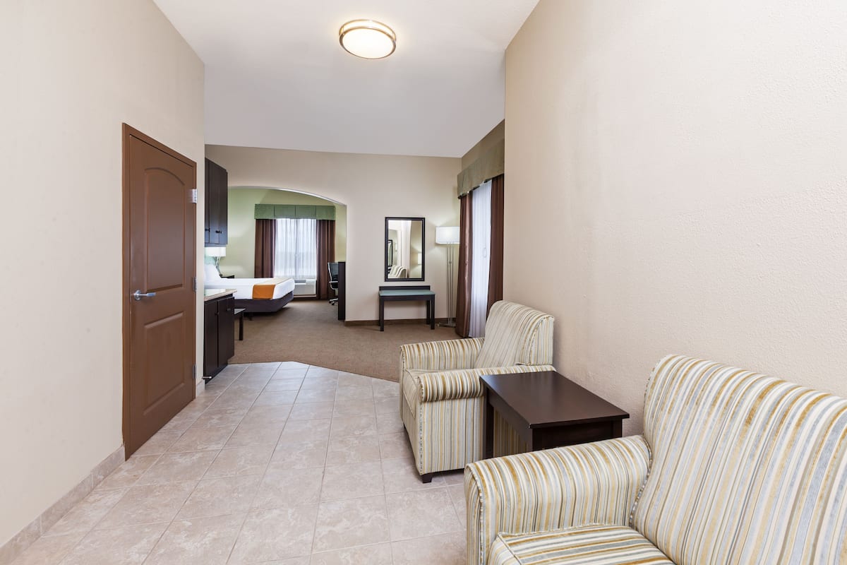A hotel room with a sofa, a small table, a bed, a desk, and a mirror.
